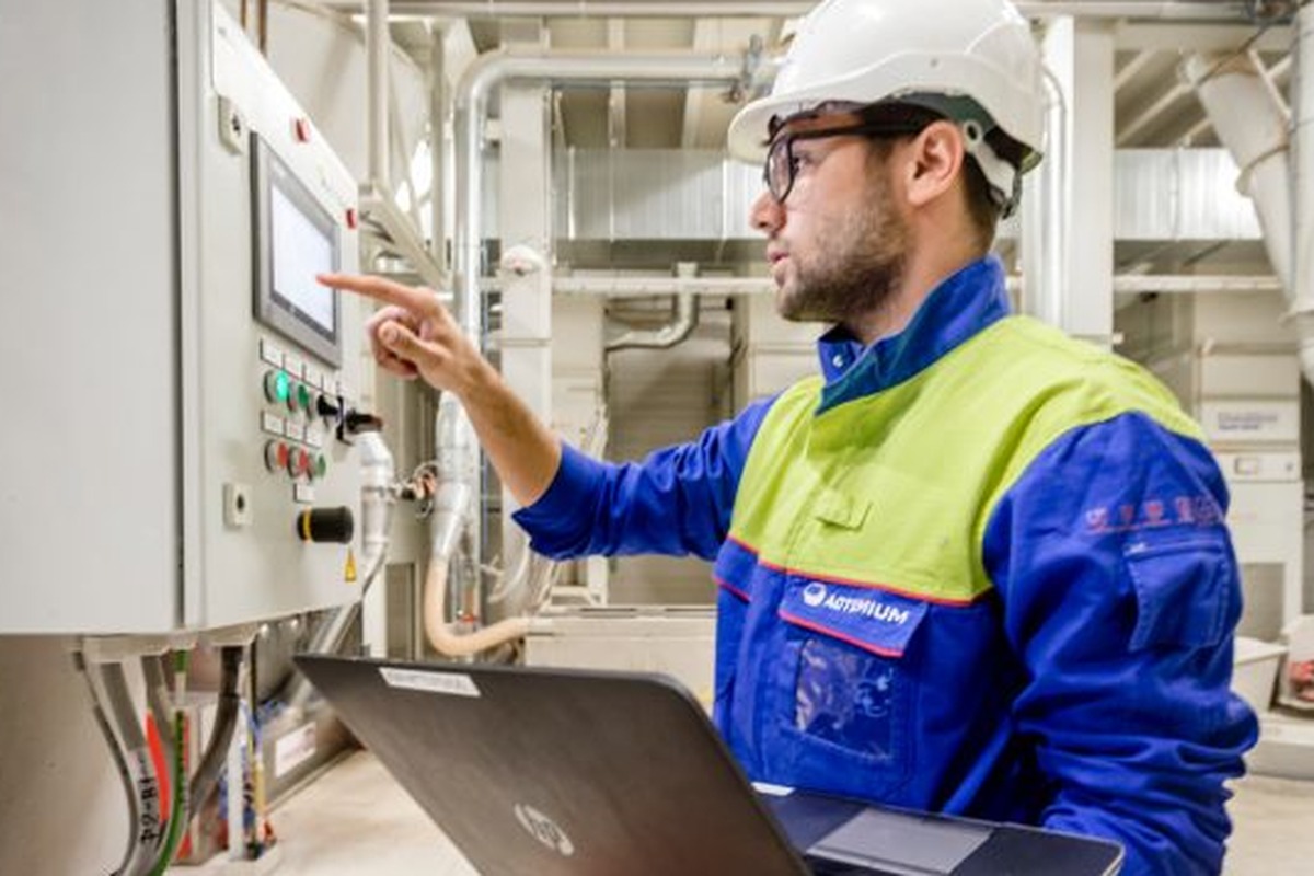 Operator gebruikt een bedieningspaneel en laptop voor monitoring en aansturing van een productieproces in een industriële omgeving. Actemium in Nederland.