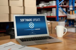 Laptop met software-update scherm in een magazijnomgeving, gebruikt voor het beheren en actualiseren van industriële software- en automatiseringssystemen. Actemium in Nederland.