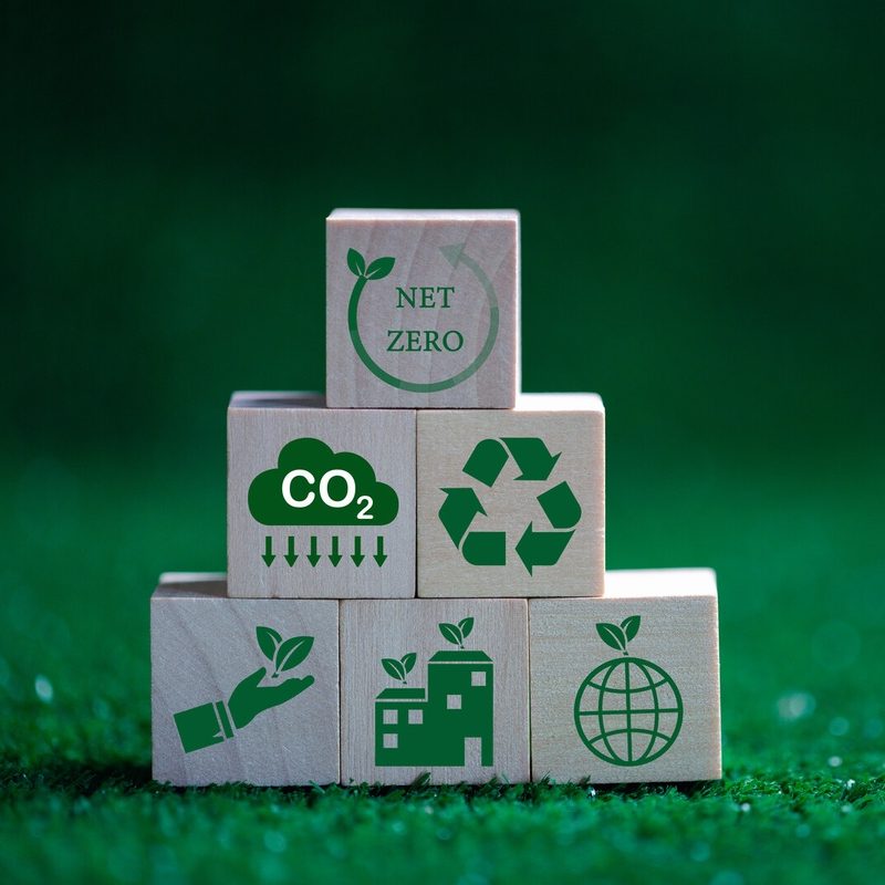 Houten blokken met symbolen voor CO₂-reductie, recycling en circulaire economie als illustratie van duurzame verpakkingsmaterialen. Actemium in Nederland.
