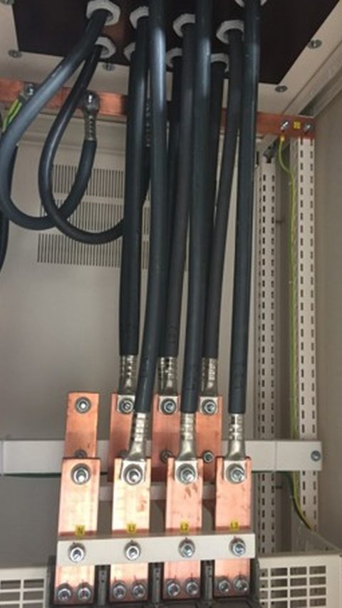 Detailfoto van een energieverdeelinrichting met koperrails, voedingskabels en aardingsaansluitingen in een technische schakelkast. Actemium realiseert en onderhoudt betrouwbare energievoorzieningen voor gebouwen en industriële installaties, met aandacht voor veiligheid, continuïteit en een efficiënte stroomverdeling.
