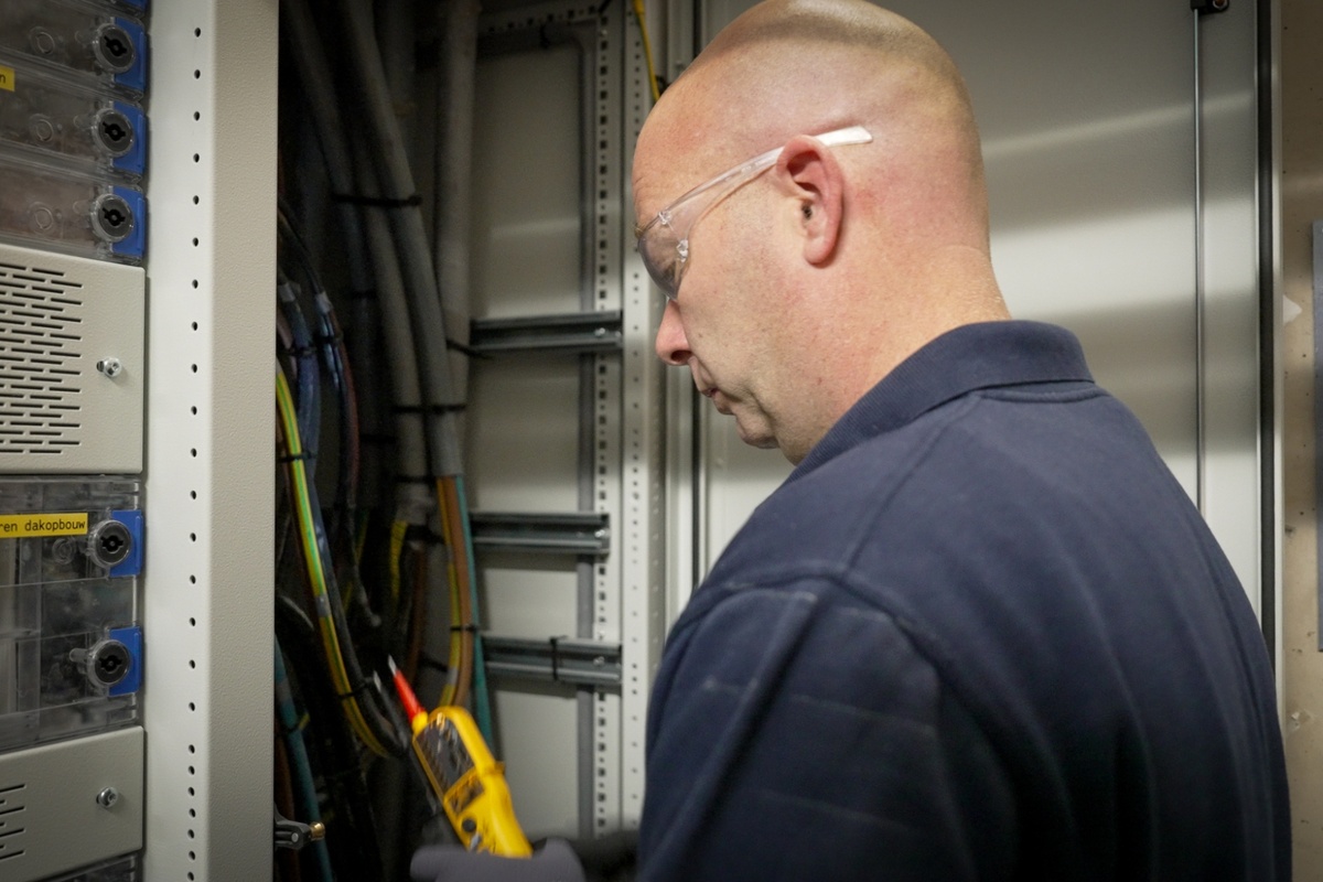 Elektromonteur gebouwgebonden installaties aan het werk bij Senefelder Misset vanuit Actemium In Doetinchem aan een elektrotechnische kast.