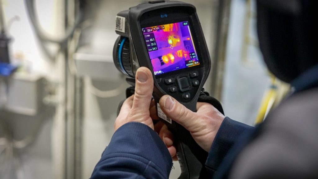 Service inspecteur aan het werk met warmtebeeldcamera bij Senefelder Misset vanuit Actemium In Doetinchem bij de klant. Thermografisch onderzoek bij paneelkast.