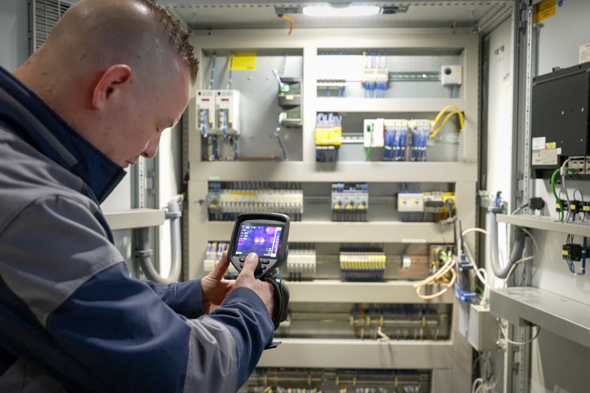 Service inspecteur aan het werk met warmtebeeldcamera bij Senefelder Misset vanuit Actemium In Doetinchem bij de klant. Thermografisch onderzoek bij paneelkast.