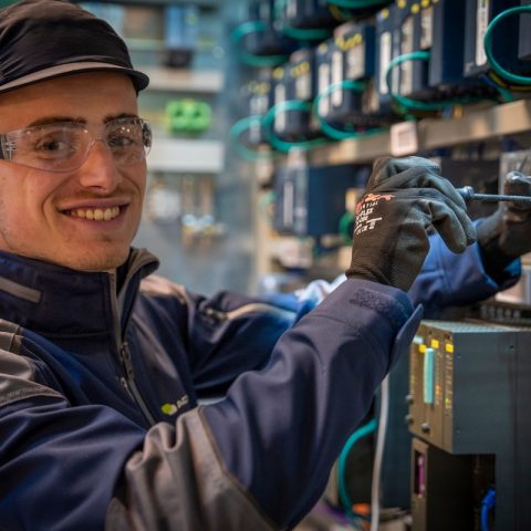 Actemium technicus voert werkzaamheden uit aan elektrotechnische installaties voor industriële elektrotechniek en instrumentatie. Op de foto is een monteur zichtbaar die een Siemens-besturingssysteem aansluit in een schakelkast, onderdeel van industriële automatiserings- en besturingsoplossingen.