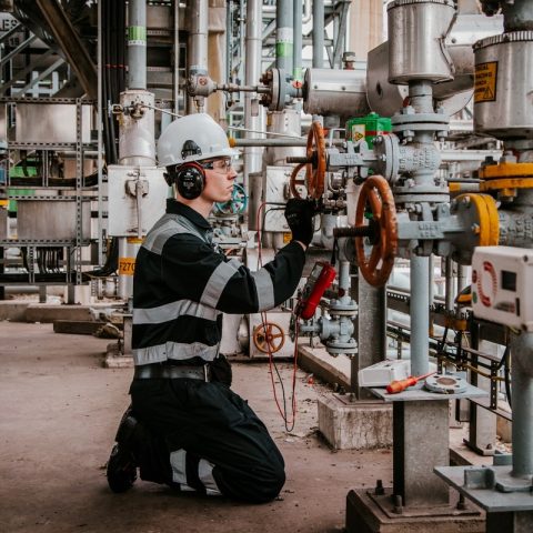 Actemium specialist inspecteert elektrotechnische installaties binnen een industriële procesomgeving. De foto toont werkzaamheden aan leidingen, afsluiters en meetinstrumentatie die bijdragen aan een veilige en betrouwbare werking van productie-installaties.