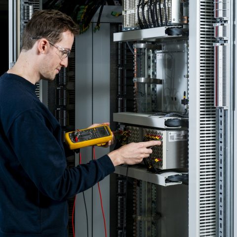 Actemium engineer controleert elektrotechnische installaties met meetapparatuur in een industriële schakelkast. De foto toont test- en inspectiewerkzaamheden aan industriële elektrotechniek en instrumentatie om een betrouwbare ingebruikname en werking te garanderen.