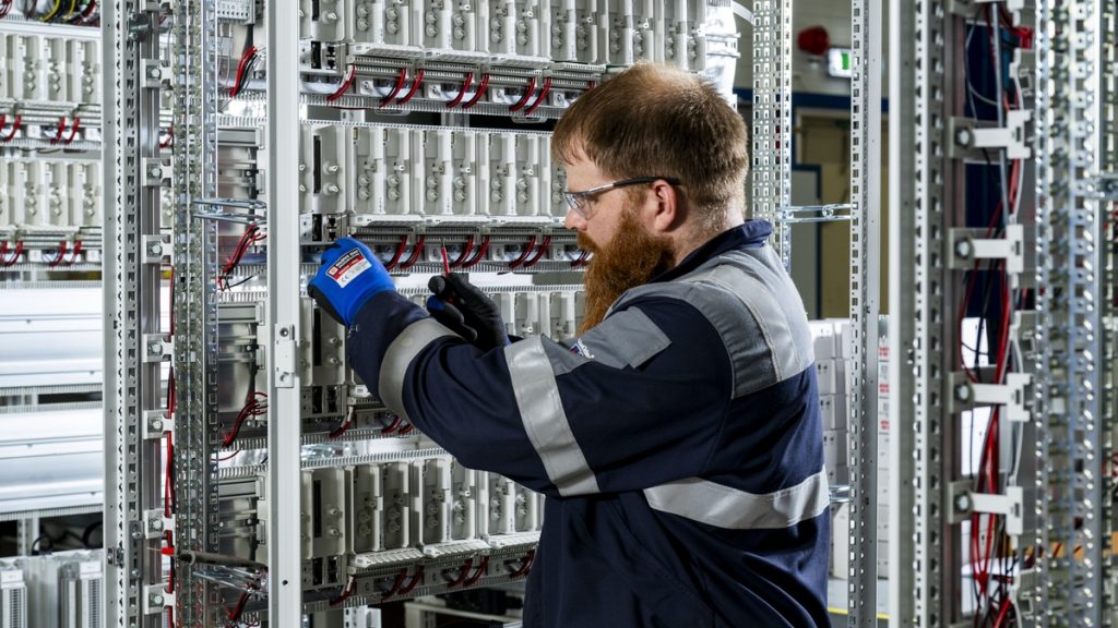 Actemium monteur werkt aan elektrotechnische installaties voor industriële elektrotechniek en instrumentatie in een besturingskast. De foto toont de montage en bekabeling van componenten in een verdeel- en besturingssysteem voor industriële processen en installaties.