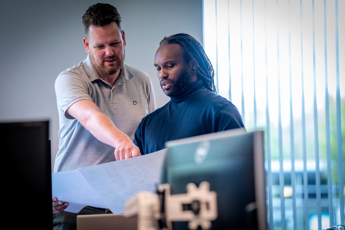 Twee specialisten van Actemium bespreken een technische tekening binnen een engineeringsomgeving. De foto toont samenwerking aan industriële automatisering, met aandacht voor besturingssystemen, software-engineering, procesautomatisering, machinebesturing en de digitalisering van industriële installaties.