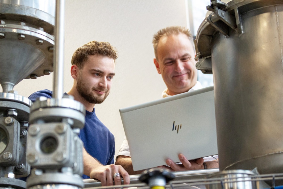Actemium zorgt voor betrouwbare en veilige industriële systemen. Op de afbeelding is een geautomatiseerde transportbaan te zien waarop blauwe bakken door een productielijn worden vervoerd.