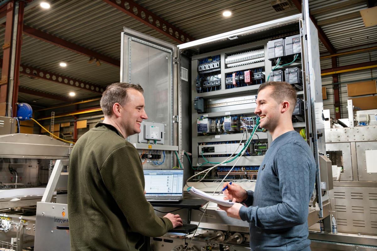 Technici voeren onderhoud en optimalisatie uit aan een industriële besturingskast binnen een geautomatiseerde productieomgeving van Actemium in Nederland.
