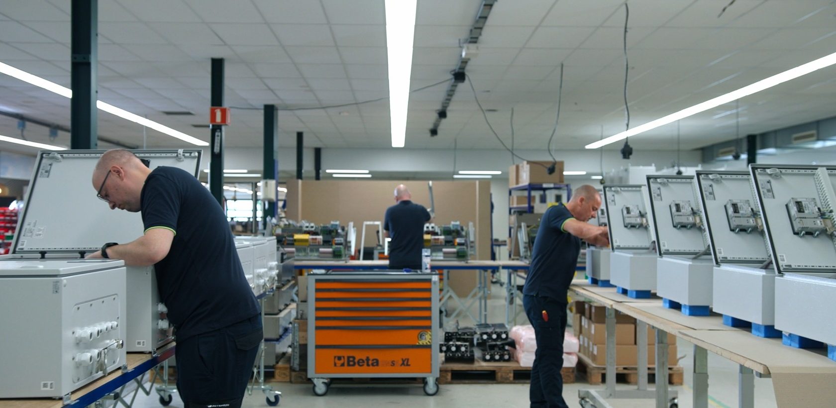 Productieomgeving waar meerdere besturingskasten gelijktijdig worden opgebouwd volgens een gestandaardiseerd productieproces voor serieproductie. Actemium in Nederland, locatie Veghel