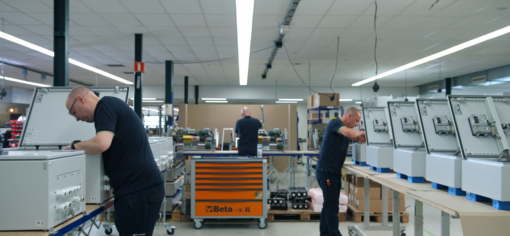 Productieomgeving waar meerdere besturingskasten gelijktijdig worden opgebouwd volgens een gestandaardiseerd productieproces voor serieproductie. Actemium in Nederland, locatie Veghel