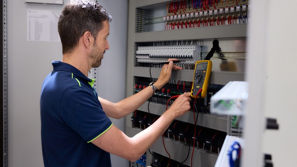 Medewerker test paneelkast met meter op spanning Actemium in Nederland locatie Schijndel