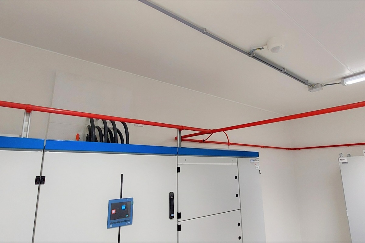 Brandmeldinstallatie met leidingwerk en technische componenten in een installatieruimte. Actemium Building Technologies levert geïntegreerde oplossingen voor branddetectie en ontruiming.