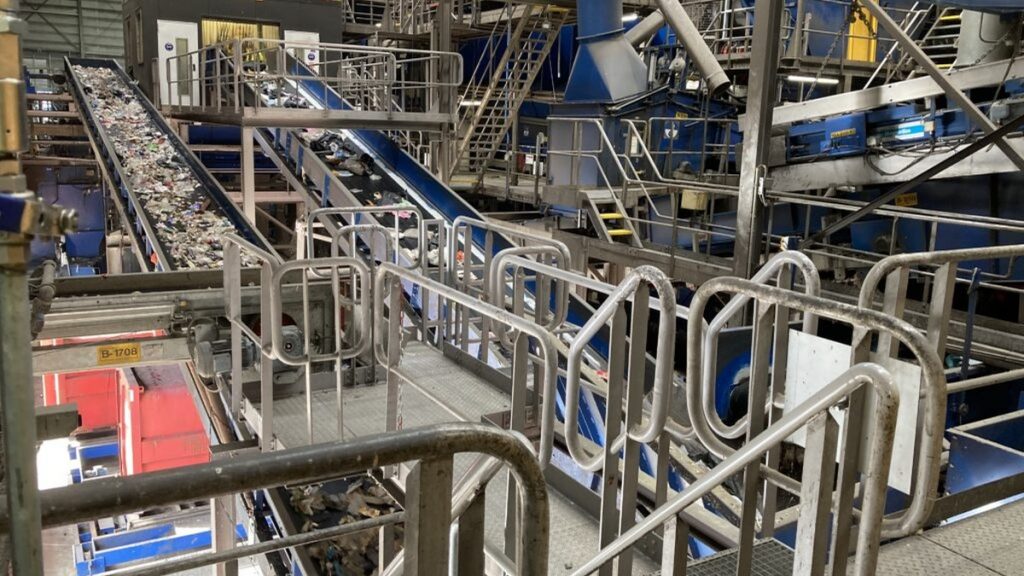 Mechanische afvalscheidingsinstallatie met transportband waarop afvalstromen worden verwerkt binnen een industriële verwerkingsomgeving.